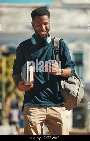 Student, education and phone with a black man university pupil walking on campus while typing a text message. Social media, communication and contact Stock Photo