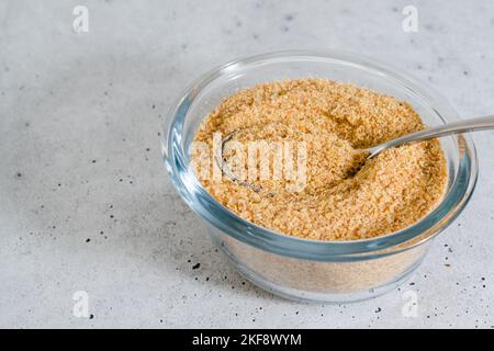 Flaxseed meal close up in a glass bowl on light grey stone background, copy space Stock Photo
