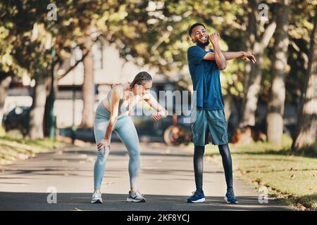 Fitness, stretching and couple rest in park after running, exercise and workout together in city. Health, wellness and interracial couple and doing Stock Photo