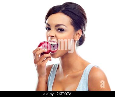 Apples... my favorite. Studio portrait of a young woman biting into an apple. Stock Photo