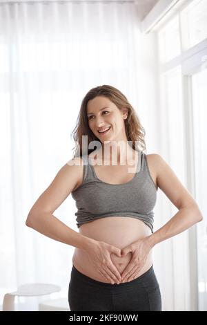 Shell love and cherish this baby. a young pregnant woman standing in her home. Stock Photo