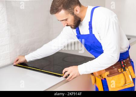 craftsman installs hob in kitchen. Household Appliance Installation Services Concept Stock Photo