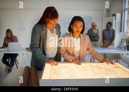 Business people, architect and floor plan in team strategy for construction, layout or design at the office. Employee women working on blueprint in Stock Photo