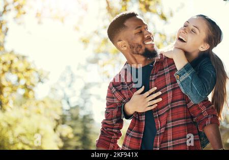 Couple, hug and smile while outdoor with love and care in nature, happy together while bonding in park. Black man, woman and interracial, hugging in Stock Photo