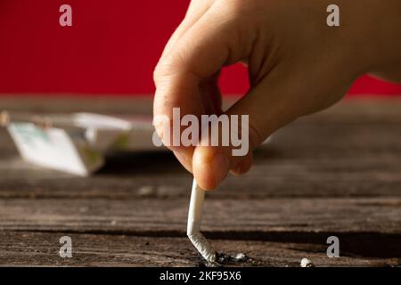 woman holding a cigarette at home at the table, smoking at home in the dark, nicotine and bad habit, cigarettes and cancer and smoking Stock Photo