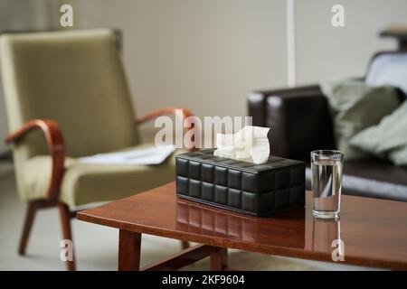 Close-up of tissues in box and glass of water preparing for psychotherapy on table at office of psychotherapist Stock Photo