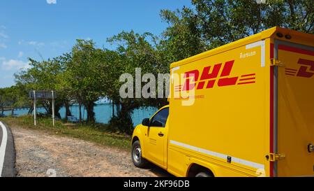 KOH CHANG, TRAT, THAILAND - 11 NOVEMBER 2022: DHL delivery van. Dhl is global market leader in logistics industry. The car is on the beach. Driver is resting in tropical exotic island at sunny day Stock Photo