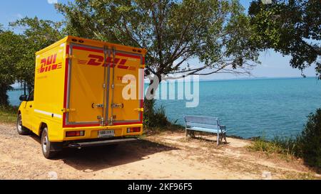 KOH CHANG, TRAT, THAILAND - 11 NOVEMBER 2022: DHL delivery van. Dhl is global market leader in logistics industry. The car is on the beach. Driver is resting in tropical exotic island at sunny day Stock Photo