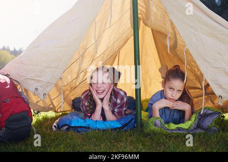 Girls only tent, no boys allowed. Two young girls lying on their sleeping bags in their tent. Stock Photo