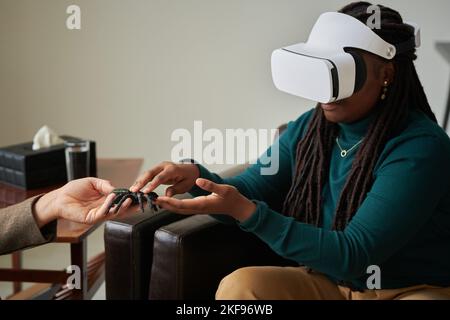 African American girl trying to overcome her phobia of spiders with virtual therapy while visiting psychologist at office Stock Photo