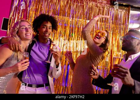 Two happy, diverse couples dancing and drinking champagne at a nightclub Stock Photo