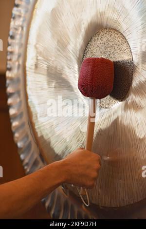 Man Playing Suspended Gong During Spiritual Practice Stock Photo