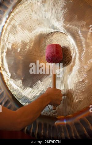 Man Playing Suspended Gong During Spiritual Practice Stock Photo