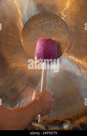 Man Playing Suspended Gong During Spiritual Practice Stock Photo