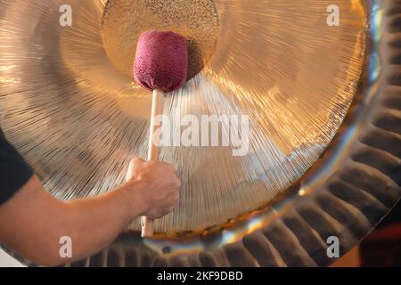 Man Playing Suspended Gong During Spiritual Practice Stock Photo