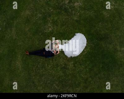 Married couple on their wedding day, laying down embracing - Drone overhead photography aerial view Stock Photo