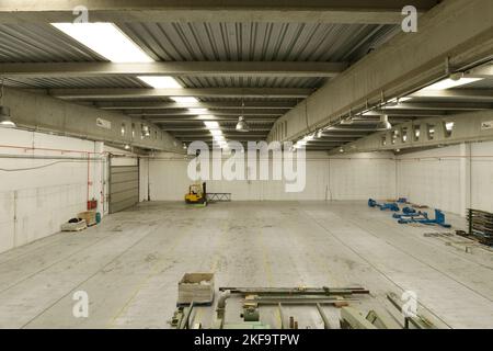 A large empty industrial warehouse with concrete floors and skylights on the roofs Stock Photo