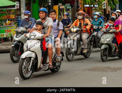 Saigon Street Life.  A father does the school run with his two kids. A rush hour motorcycle swarm in Ho Chi Minh City Stock Photo