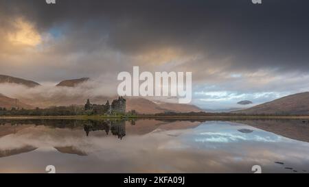 Scottish castle by the side of the loch. Beautiful reflection of the red, grey and white clouds. Stunning Scottish landscape image. Kilchurn Castle Stock Photo