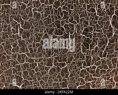 Brown decorative plaster with aging effect. Bronze background with white cracked paint. Texture backdrop. Stock Photo