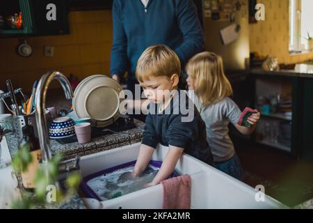 Children helping father washing dishes in the kitchen Stock Photo