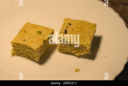 Two pieces of Indian Sweets, Soan Papdi served on a white plate. Stock Photo