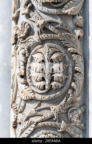 Close-up on decorative floral sculptures carved on stone pillar of exterior facade of italian catholic church in Pisa Stock Photo