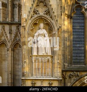 Elizabeth 2 limestone statue standing on high niche wearing ceremonial dress (orb & sceptre) - west front, York Minster, North Yorkshire, England, UK. Stock Photo