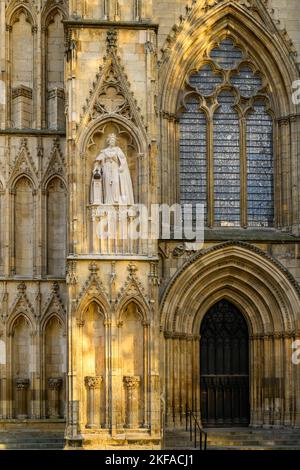 Elizabeth 2 limestone statue standing on high niche wearing ceremonial dress (orb & sceptre) - medieval York Minster, North Yorkshire, England UK. Stock Photo