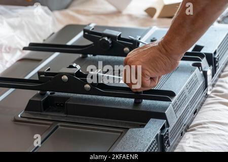 A Handyman using a screwdriver to fix a window handle tv Stock Photo