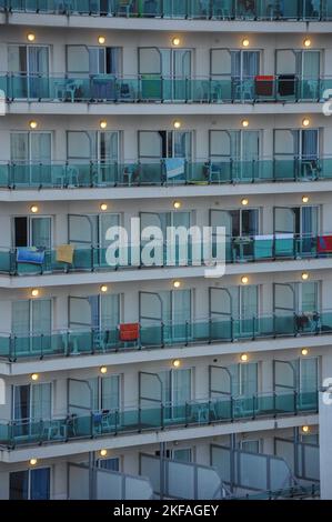 A closeup shot of balconies of a beach hotel, at night, with lights on, and towels over the fences, drying, in Valencia, Spain Stock Photo