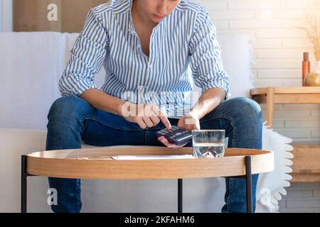 Unrecognizable young man on striped shirt calculating for investment, loand or mortage in the interior of his apartment Stock Photo
