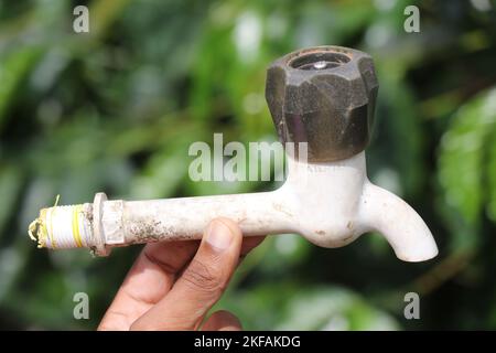Old water tap or kitchen faucet held in hand on outdoors with natural background Stock Photo