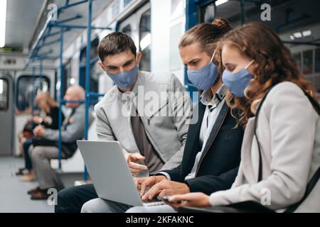 group of young people using a laptop while sitting in a subway car. Stock Photo