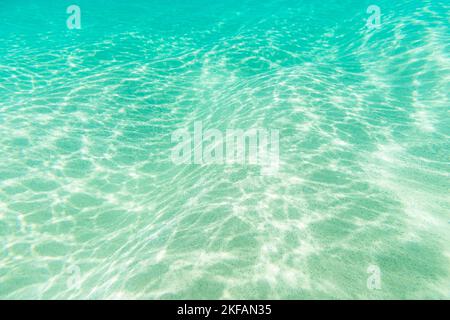 The wavy and sandy seabed in Fernando de Noronha with sun reflections on the water's surface Stock Photo