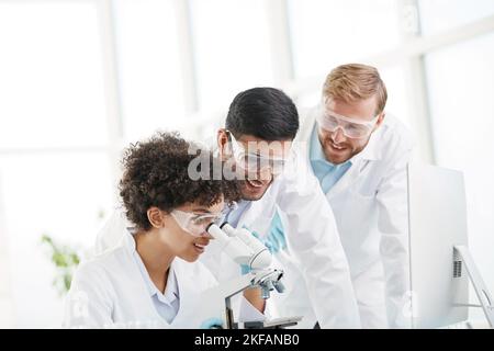 a group of young scientists discussing near the laboratory table Stock Photo