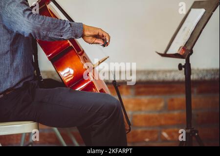 A musician playing cello with musical notes on the book notation stand in front of him Stock Photo