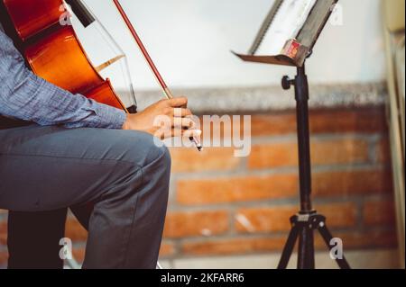 A musician playing cello with musical notes on the book notation stand in front of him Stock Photo