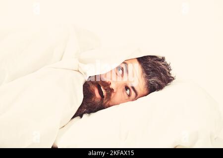 Man with beard and mustache hiding in bed under blanke Stock Photo