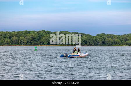 Three men in a inflatable boat fishing off the coast of shelter island, ny Stock Photo