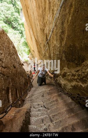 Visitor / tourist climbs steep steps cut into a stone rock face on ...