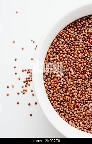 Red quinoa seeds in a white bowl close-up. Stock Photo