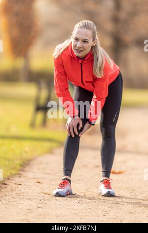 A young athlete sprained her knee while running, she holds it in pain. Stock Photo
