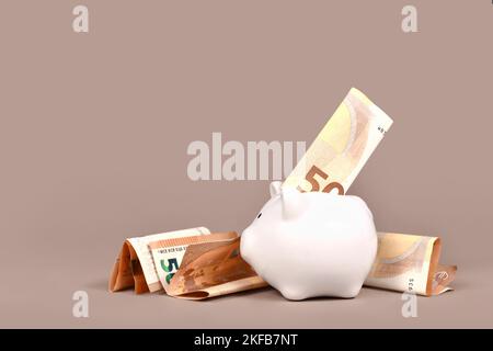White piggy bank with 50 Euro bills on beige background with copy space. Concept for saving money Stock Photo
