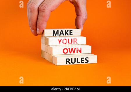 Make your own rules symbol. Concept words Make your own rules on wooden cubes. Beautiful orange table orange background. Businessman hand. Business mo Stock Photo