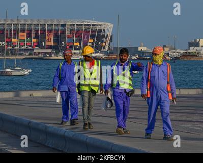 DOHA 20221116 Workers on the famous Corniche promenade in Doha with the Ras Abu Aboud Stadium in the background ahead of the FIFA World Cup in Qatar w Stock Photo