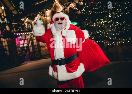 Photo of funky crazy grandpa hipster rock roll music lover hand demonstrate horns gesture carry presents walking street outdoor Stock Photo