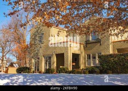 Entrance of landscaped stucco two story house with snow on the ground in upscale neighborhood Stock Photo