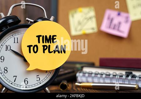 Business concept. The alarm clocks have a sticker with the inscription - TIME TO PLAN. There are office items in the background in a blurry background Stock Photo