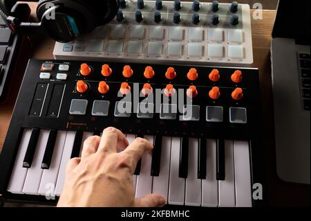 Close-up. Musician's hand on a professional synthesizer, midi keyboard and studio headphones. Sound work, podcast, arrangement. Musician, composer, so Stock Photo